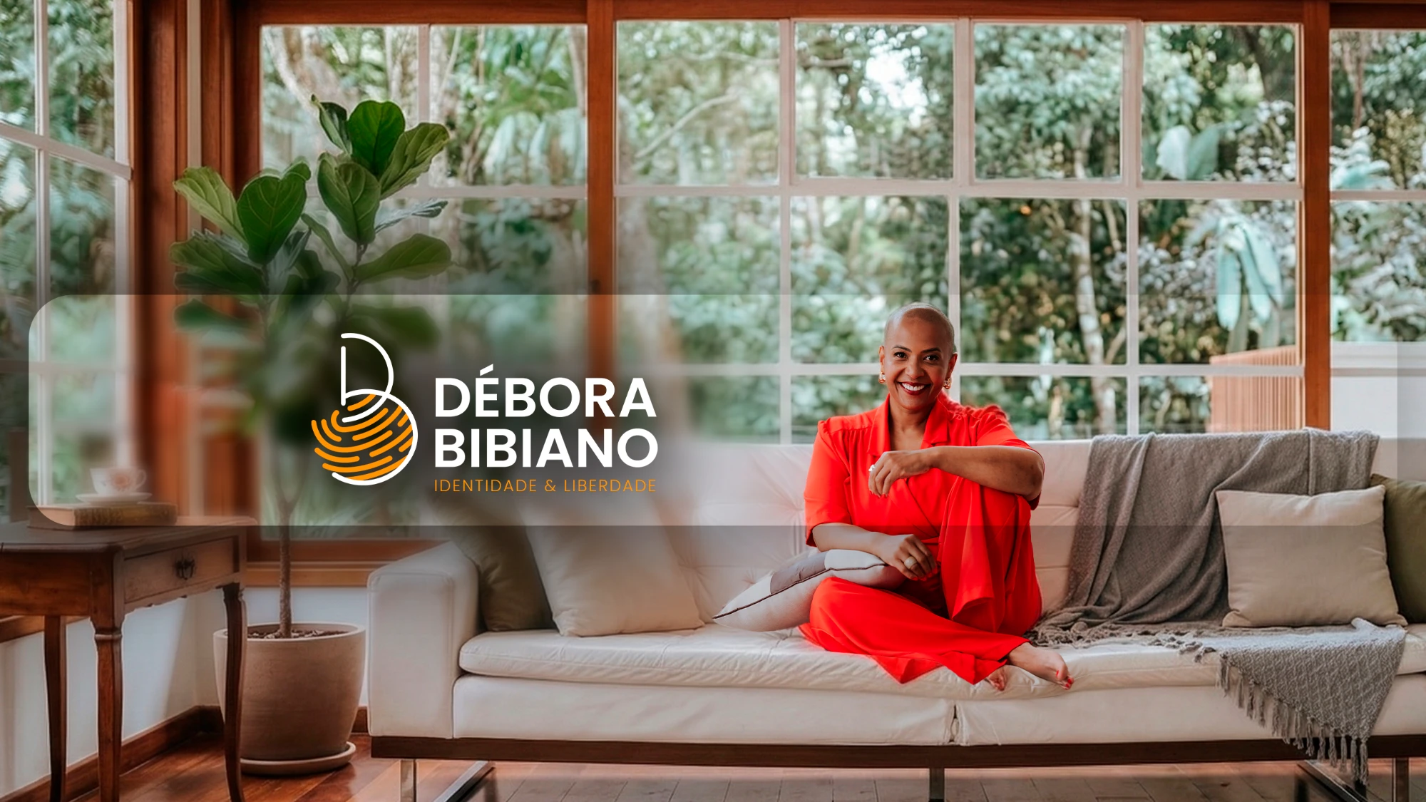 Débora Bibiano sorrindo, sentada em um sofá branco, ao lado do logotipo Débora Bibiano – Identidade & Liberdade